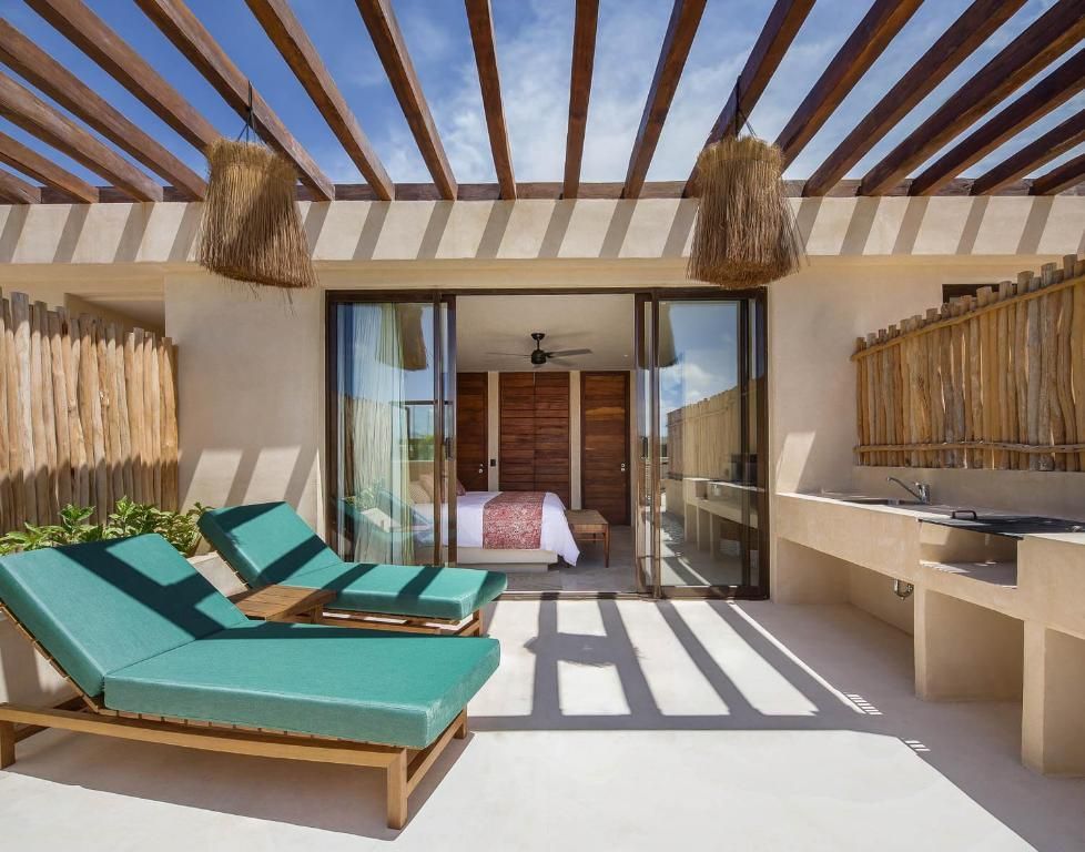 A patio with chairs and a sliding glass door leading to a bedroom.