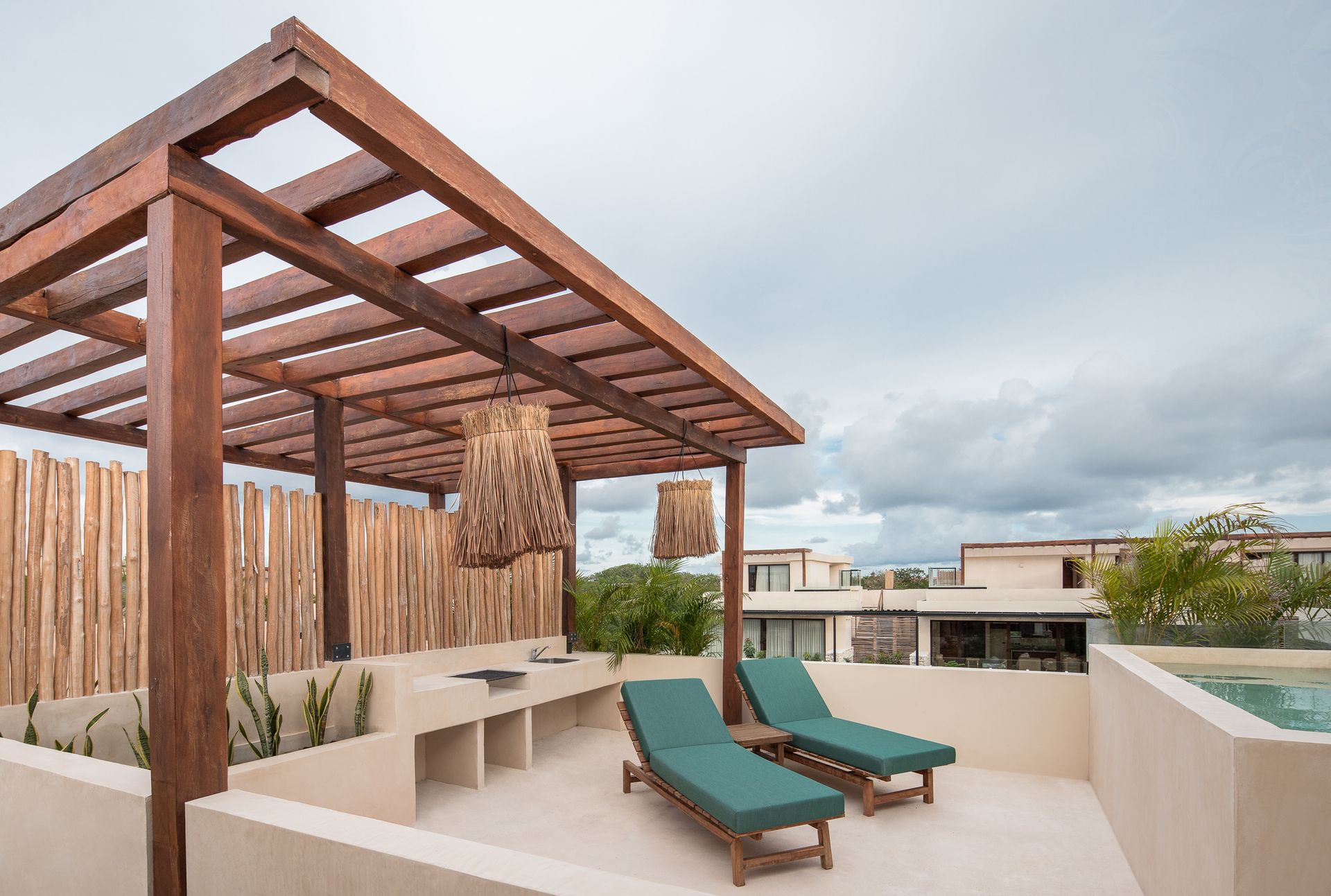 A rooftop deck with a wooden pergola and two lounge chairs.