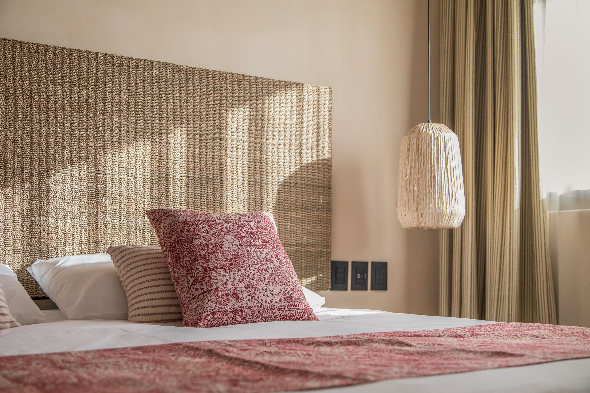 A bed with a wicker headboard and pillows in a hotel room.