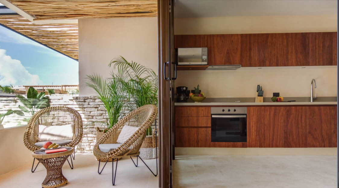 A kitchen and a balcony with wicker chairs and a table.