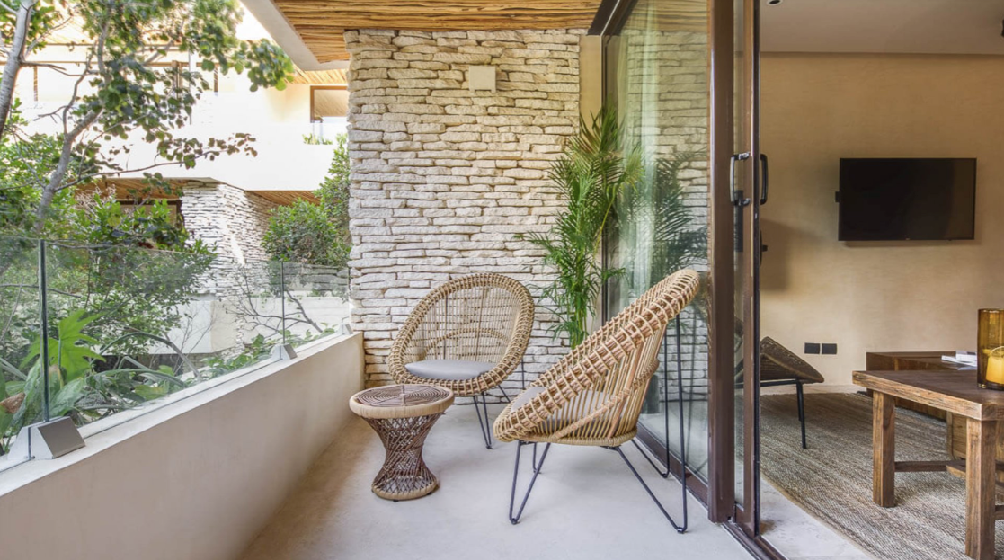 A balcony with two wicker chairs and a table in a living room.
