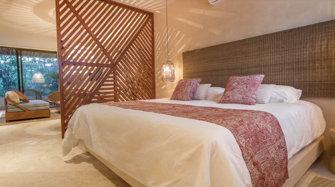 There is a bed in the middle of the room with a wooden divider.