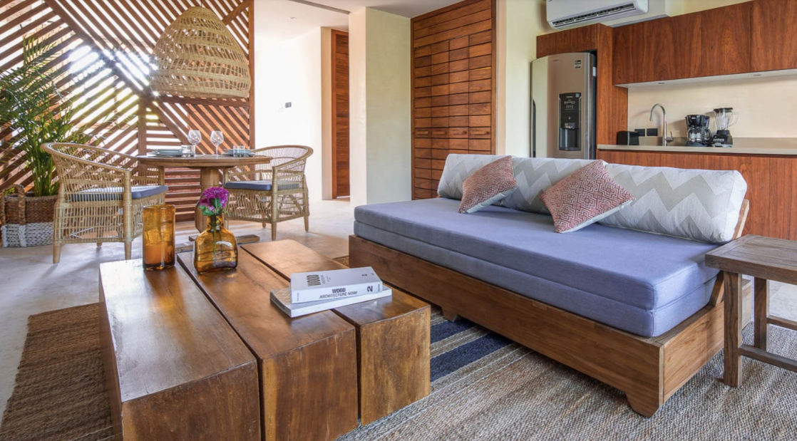 A living room with a couch , table , chairs and a kitchen.