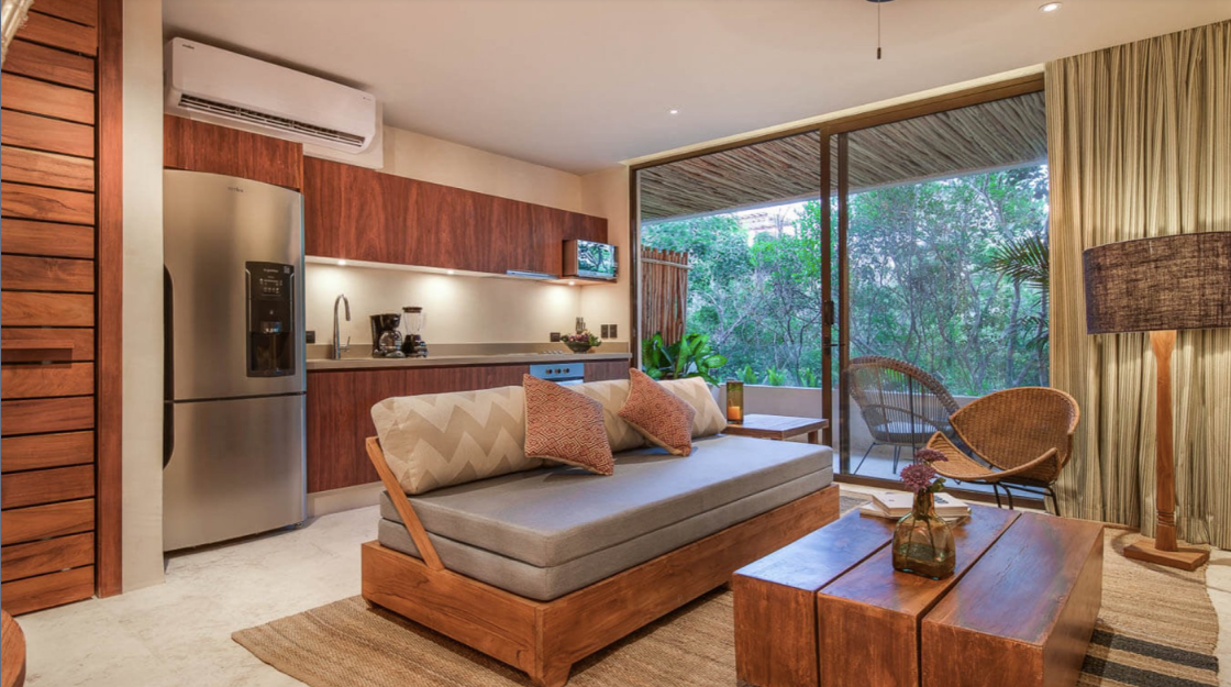 A living room with a couch , table , chairs and a kitchen.