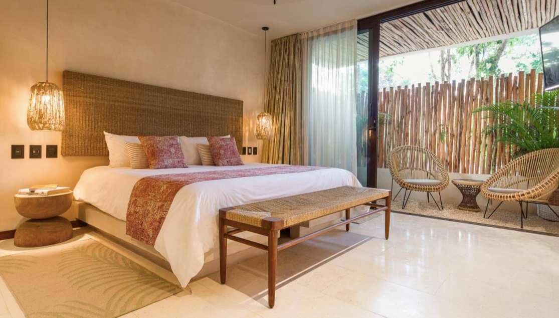 A hotel room with a king size bed and a bench.