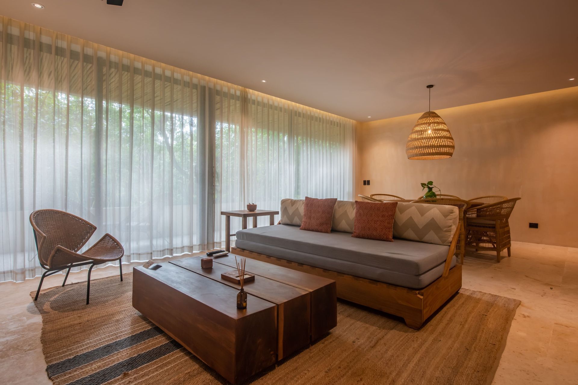 A living room with a couch , table , chairs and curtains.