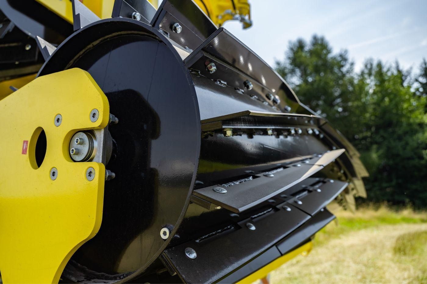 Yellow farm machine harrowing a harvested corn field.