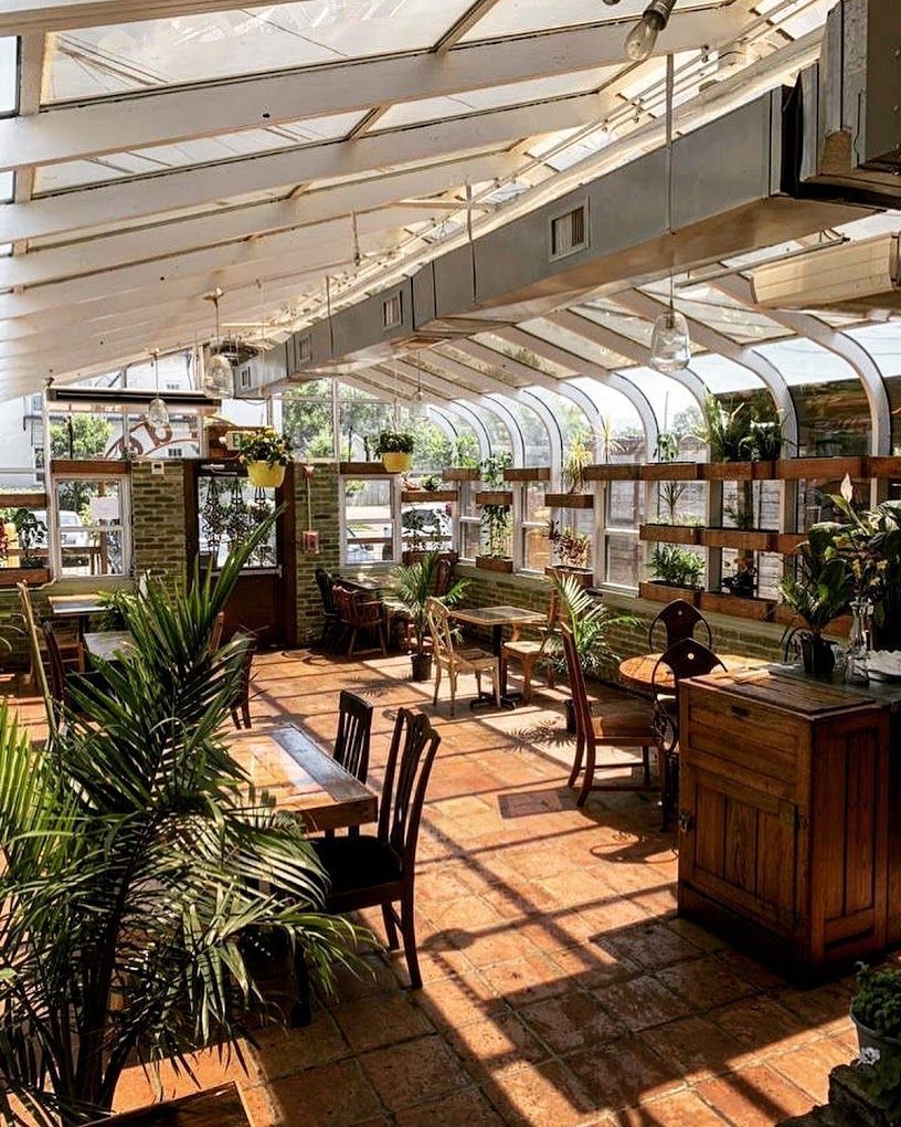 A restaurant with tables and chairs in a greenhouse