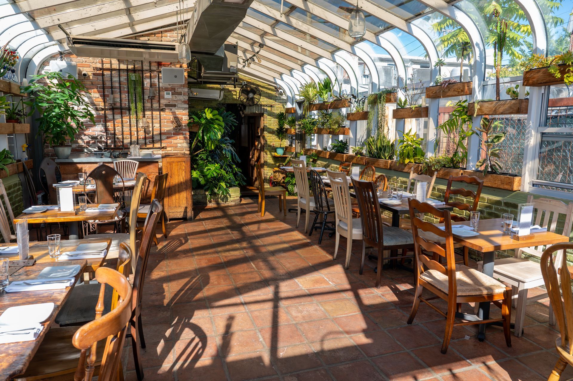 A restaurant with tables and chairs in a greenhouse.