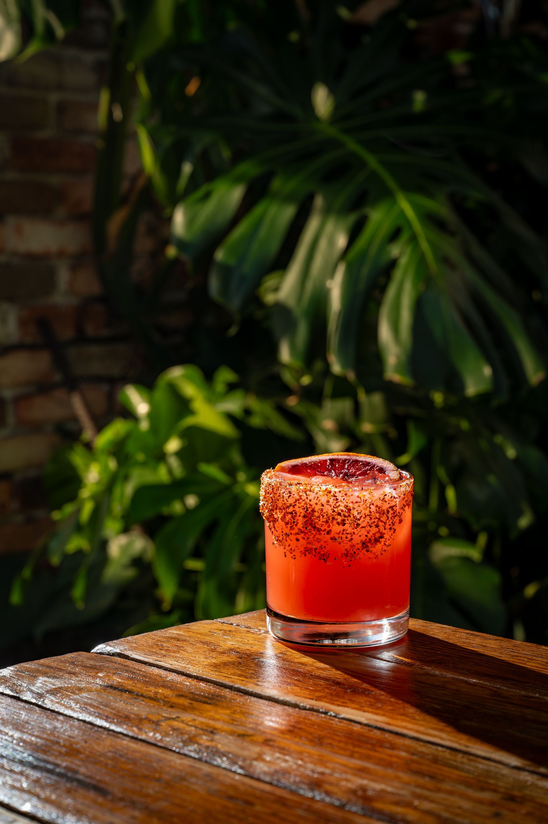 A glass of red liquid is sitting on a wooden table.
