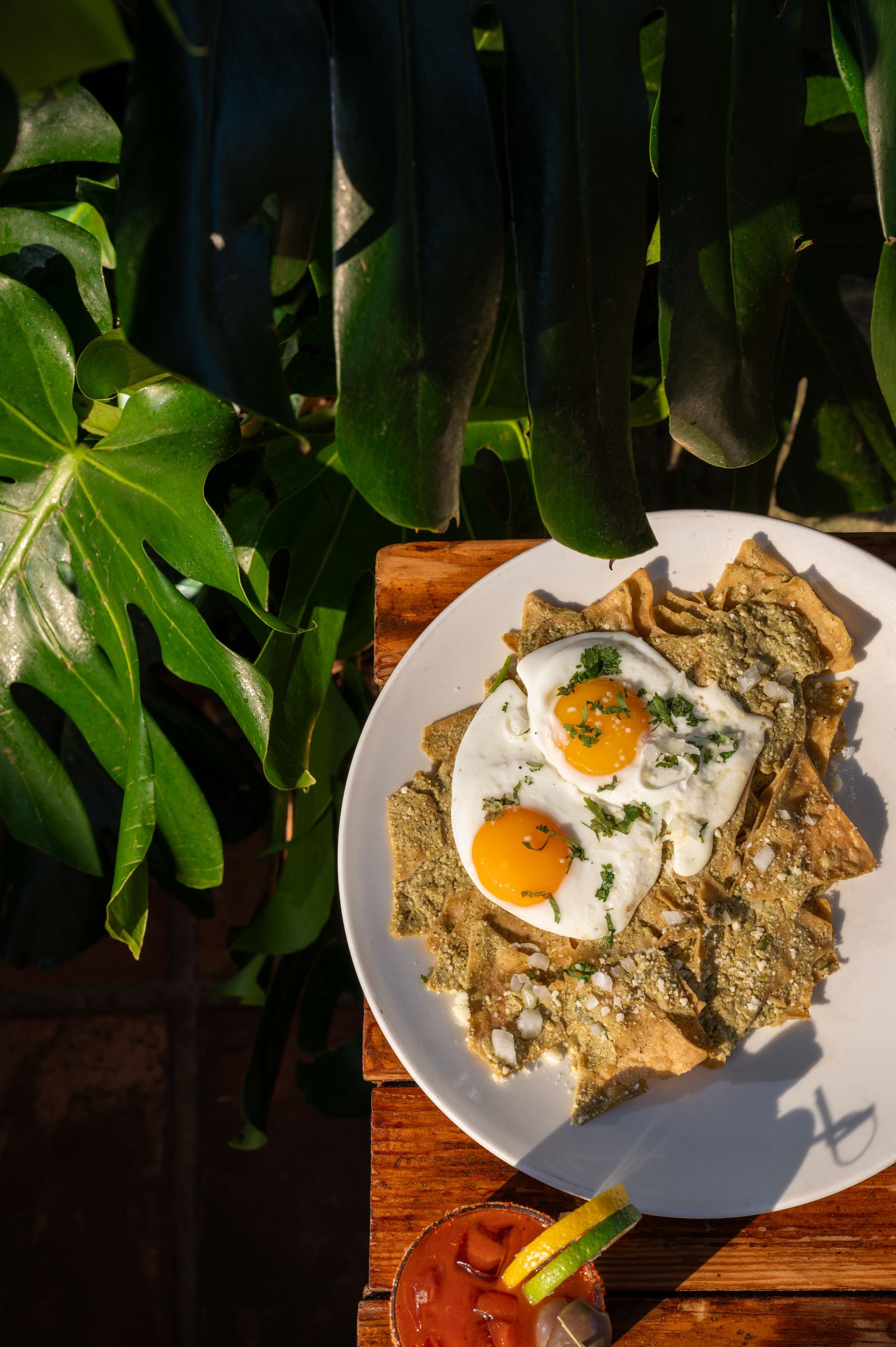 A plate of food with eggs and nachos on a wooden table.