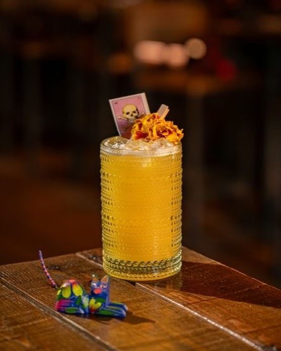 A close up of a drink in a glass on a wooden table.