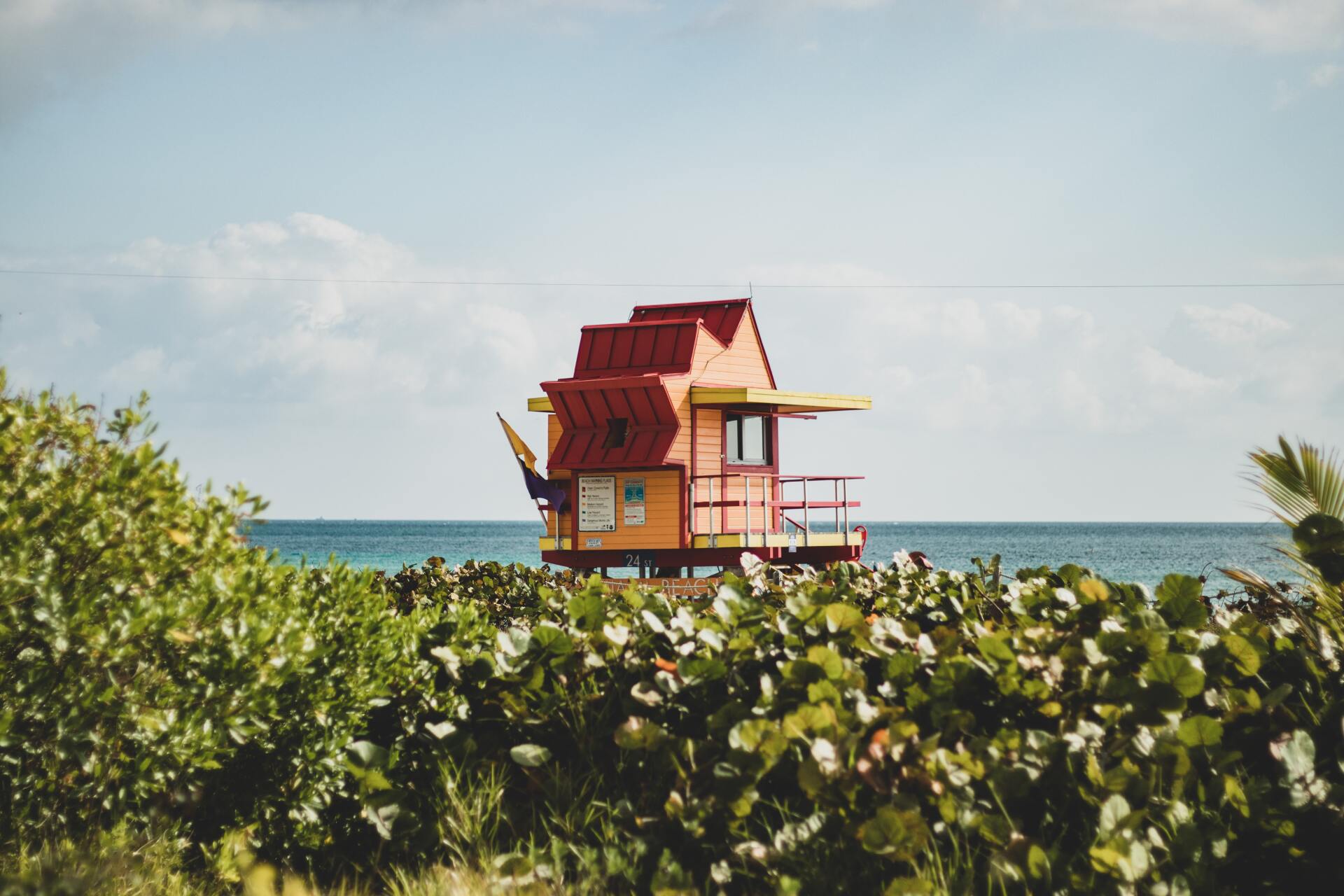 A lifeguard tower is sitting on top of a grassy hill overlooking the ocean.
