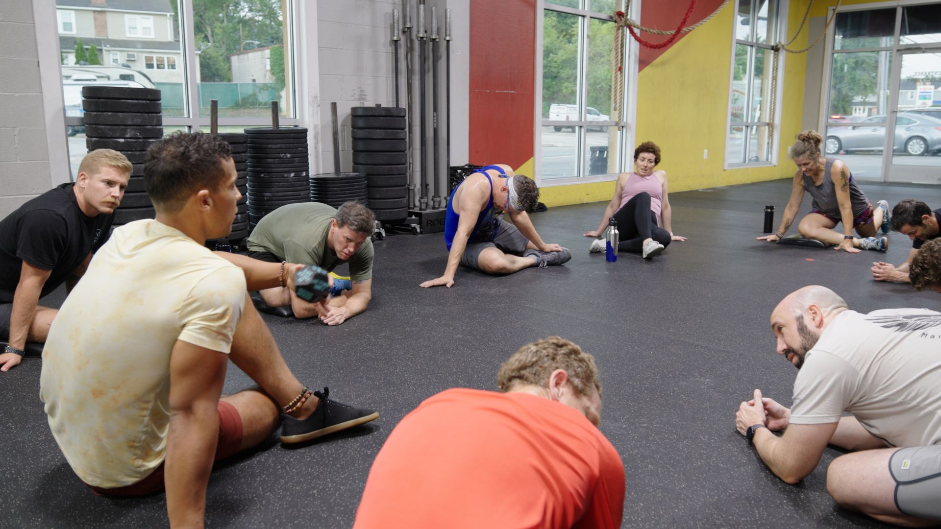 A group of people are sitting on the floor in a gym.