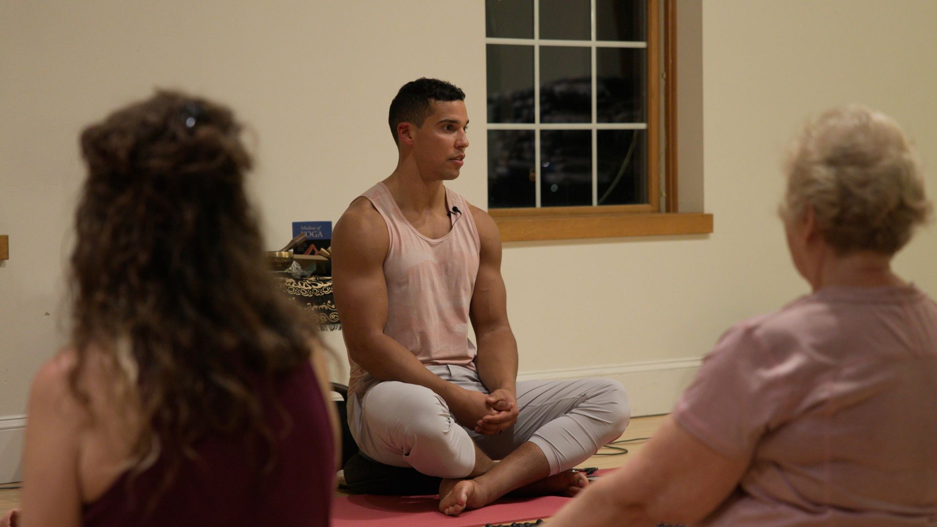 A group of people are sitting on a yoga mat in a room.