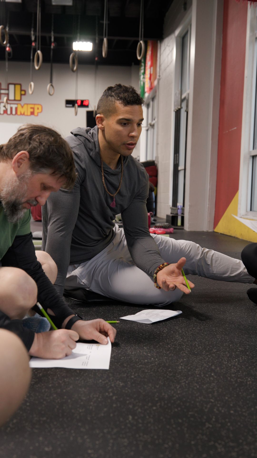 A group of men are sitting on the floor in a gym.