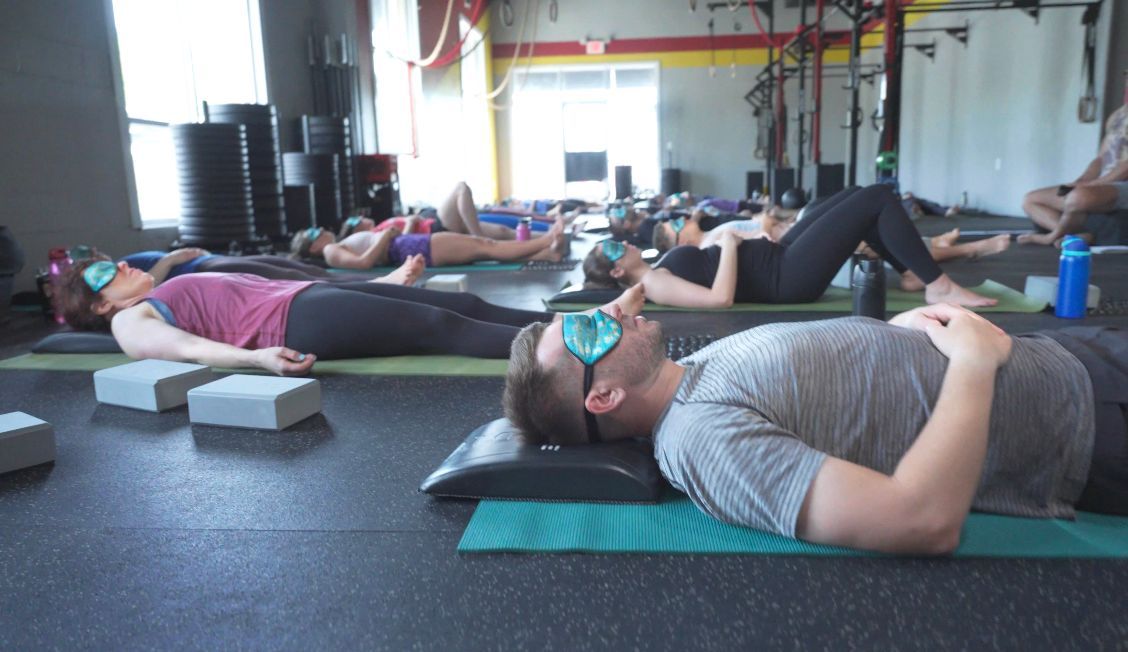 A group of people are laying on yoga mats in a gym.