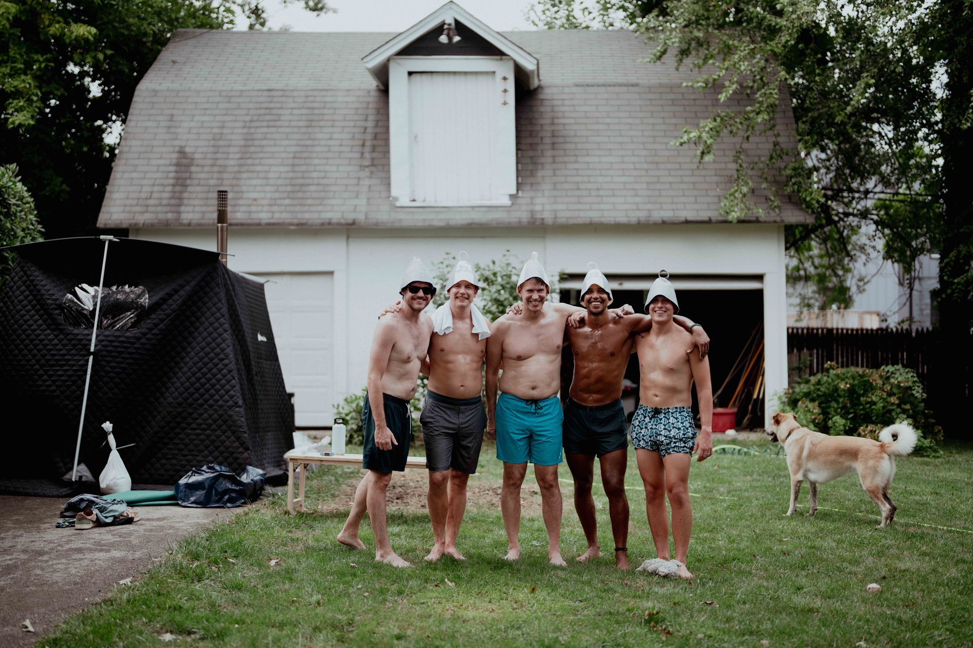 A group of men are posing for a picture in front of a house.