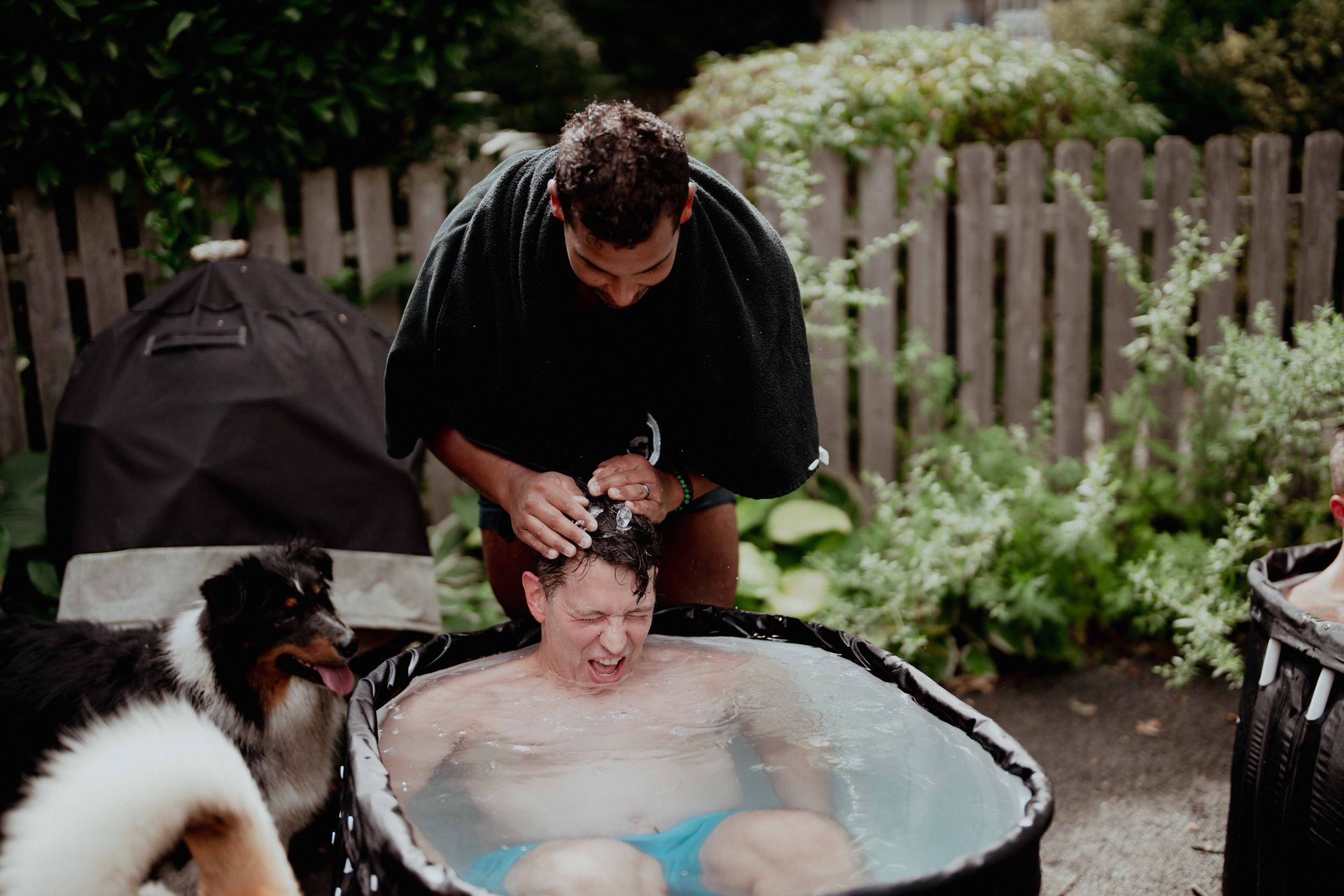 A man is washing another man 's hair in a hot tub.