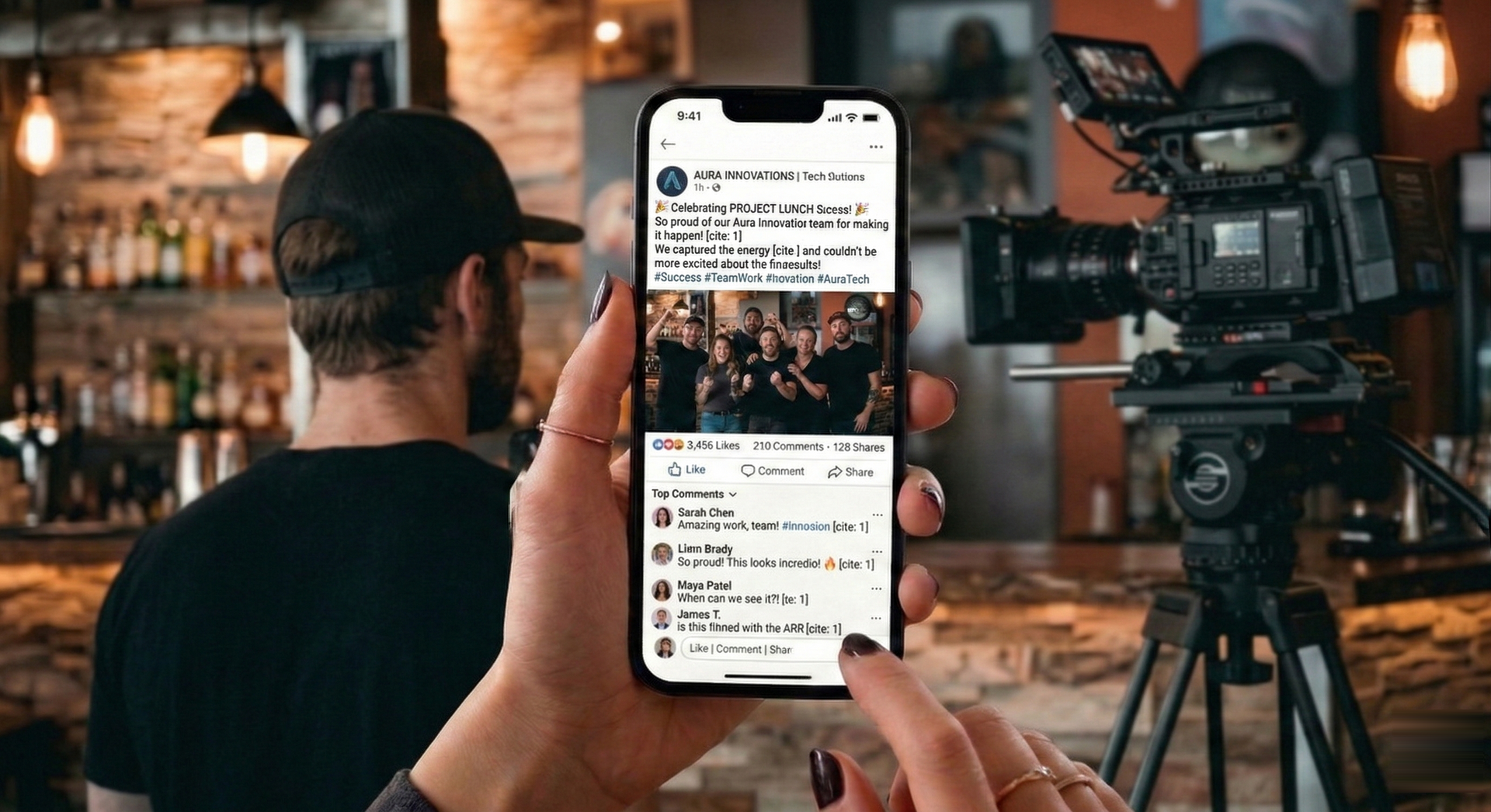 Person holding phone displaying social media posts in front of a camera and another person, in a bar setting.