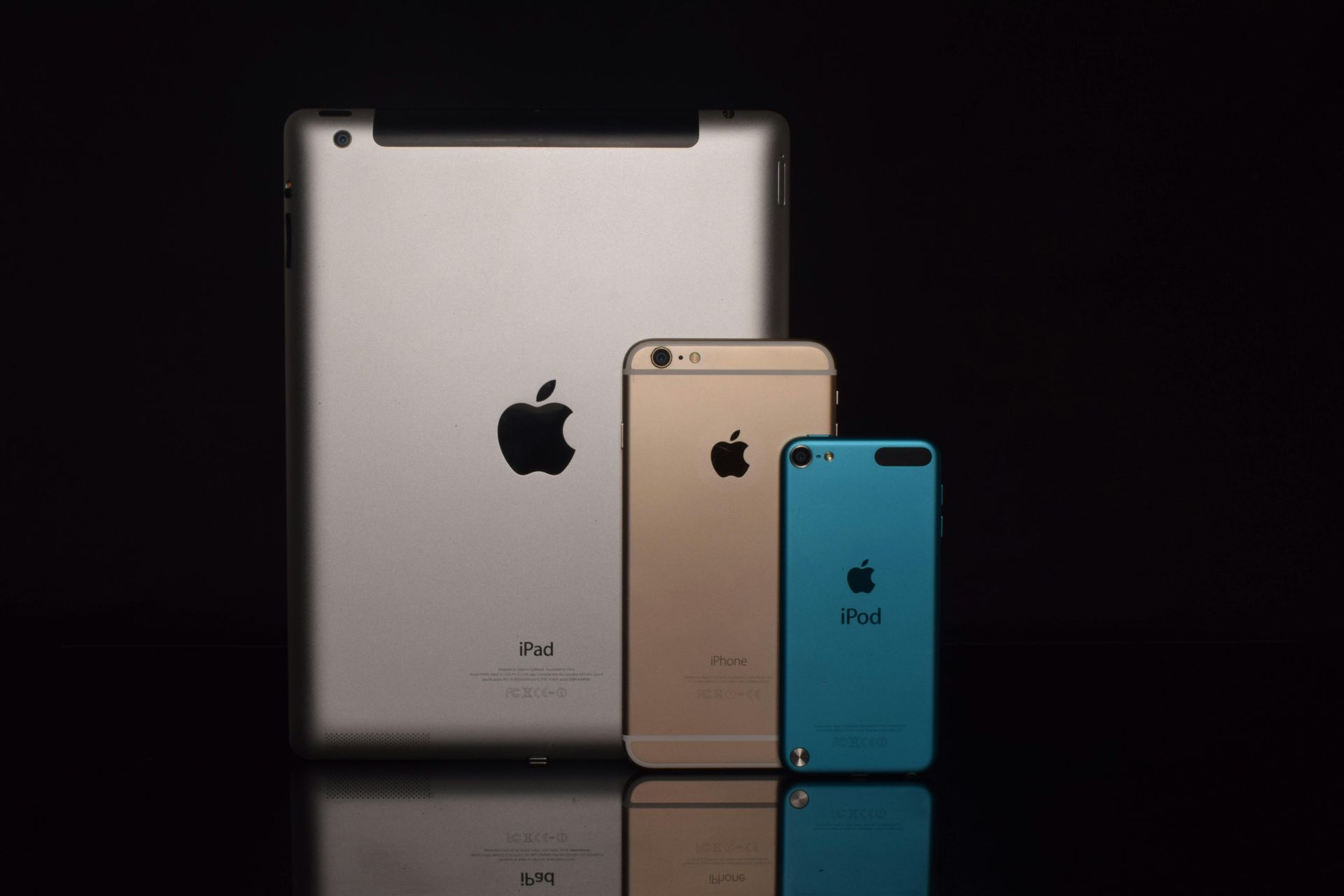 Three apple devices are sitting next to each other on a table. Three apple devices are sitting next to each other on a table.