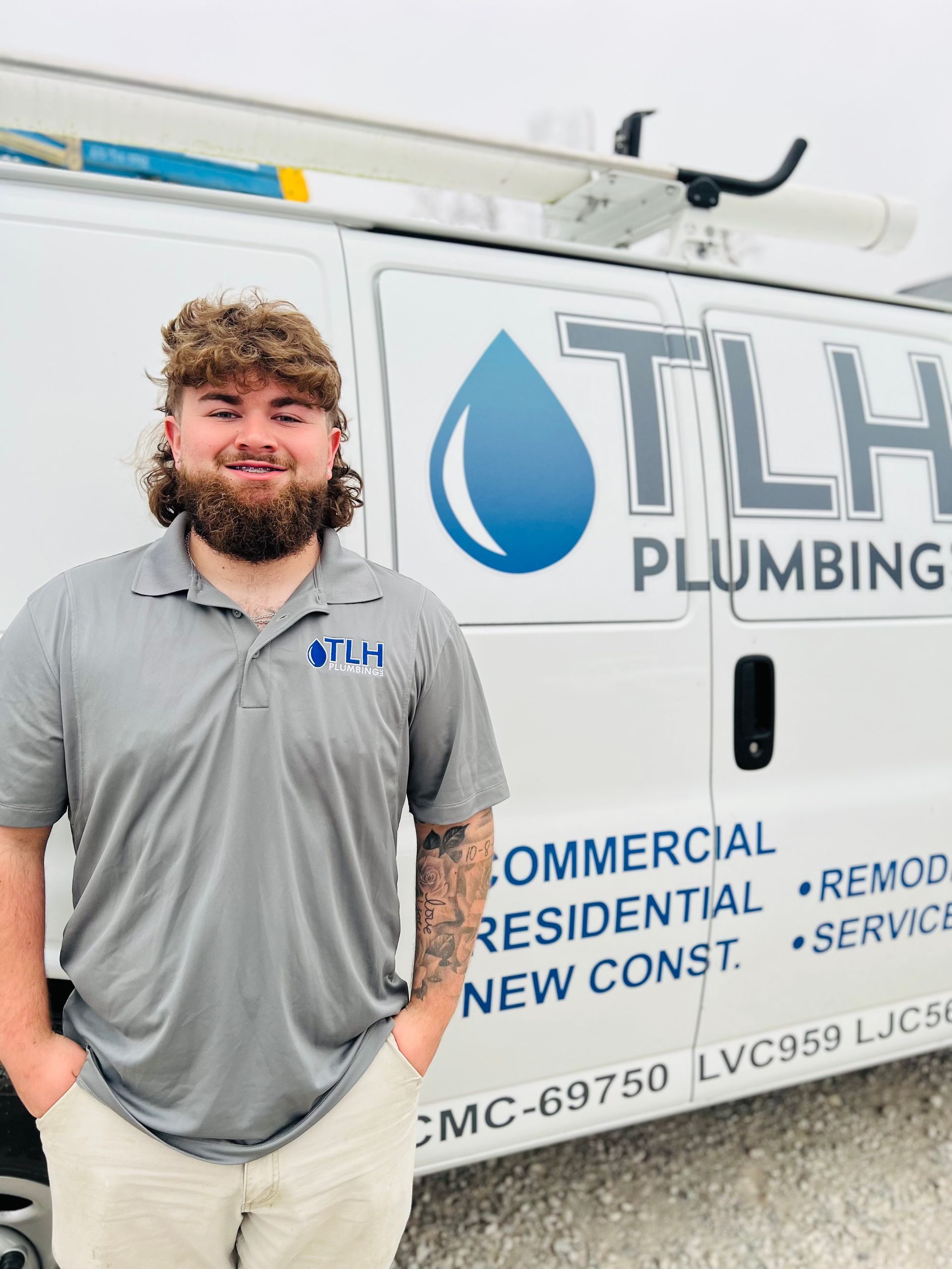 Man in gray shirt stands in front of a white plumbing van with TLH Plumbing logo.