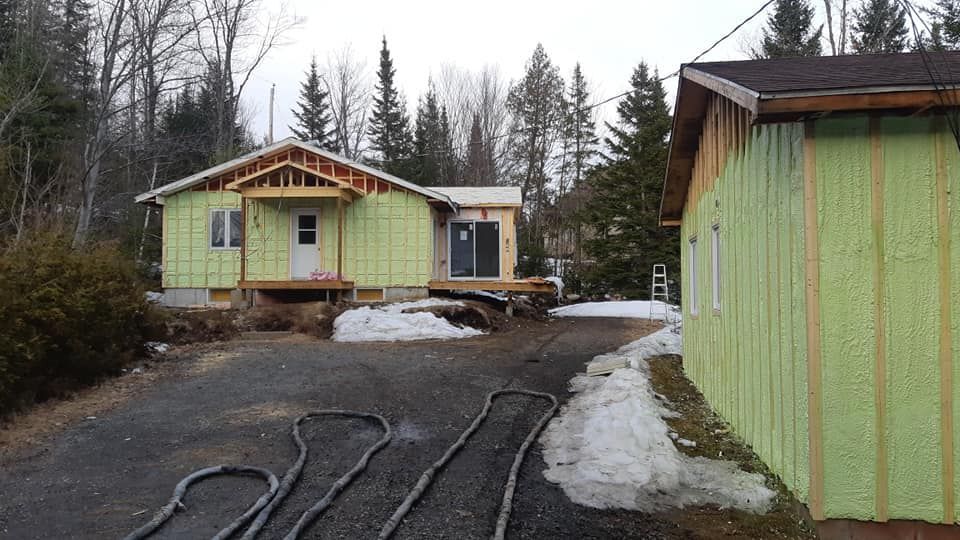 Maison en construction; isolation vert clair, allée foncée, plaques de neige.