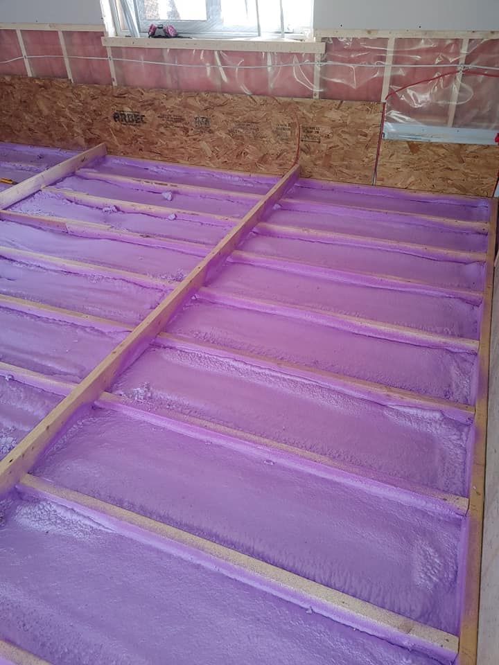 L'isolant violet remplit les solives de plancher d'un sous-sol pendant la construction.