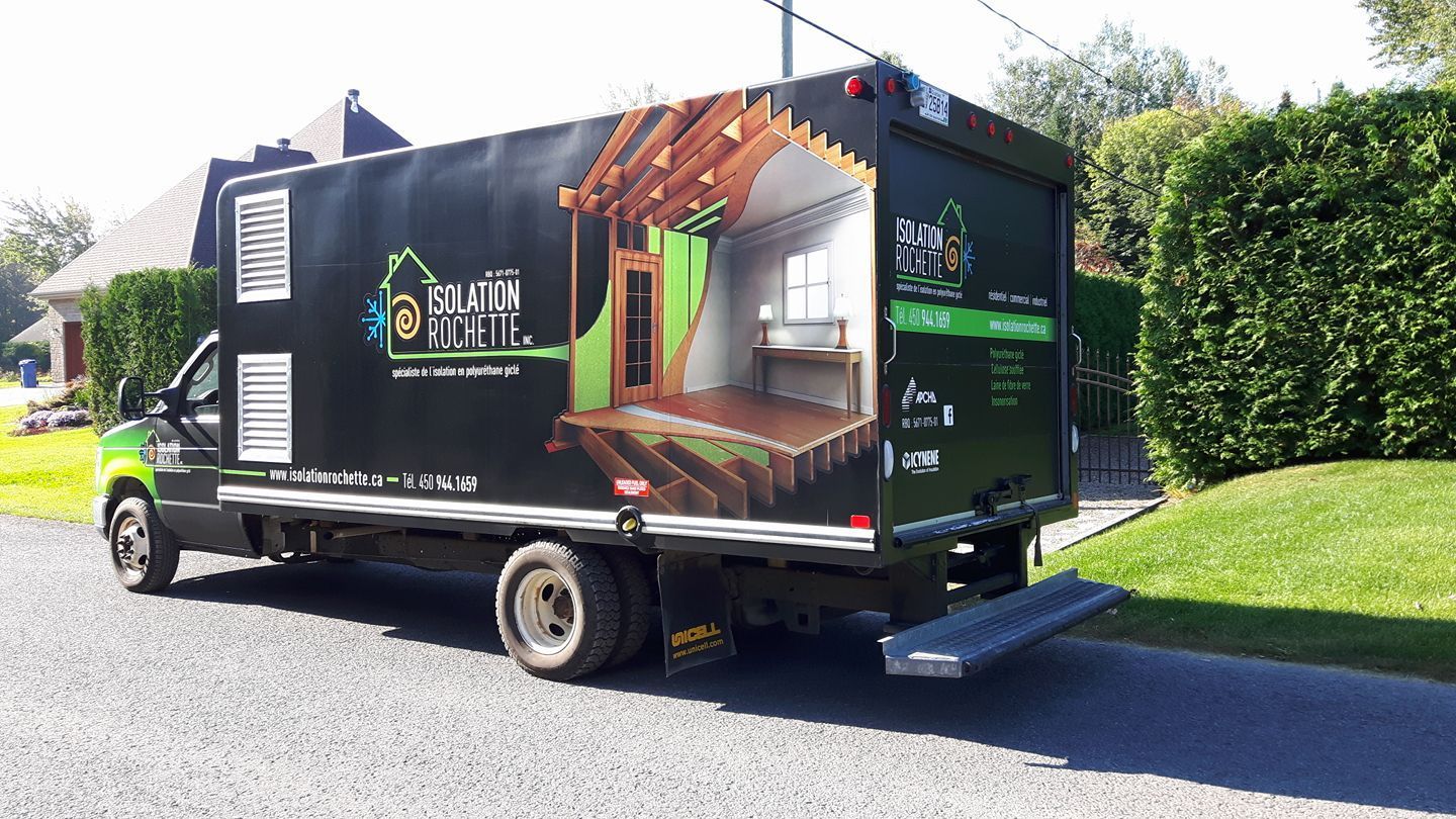 Camion de déménagement avec un graphique de construction de maison garé sur une allée, de l'herbe verte et une maison en arrière-plan.