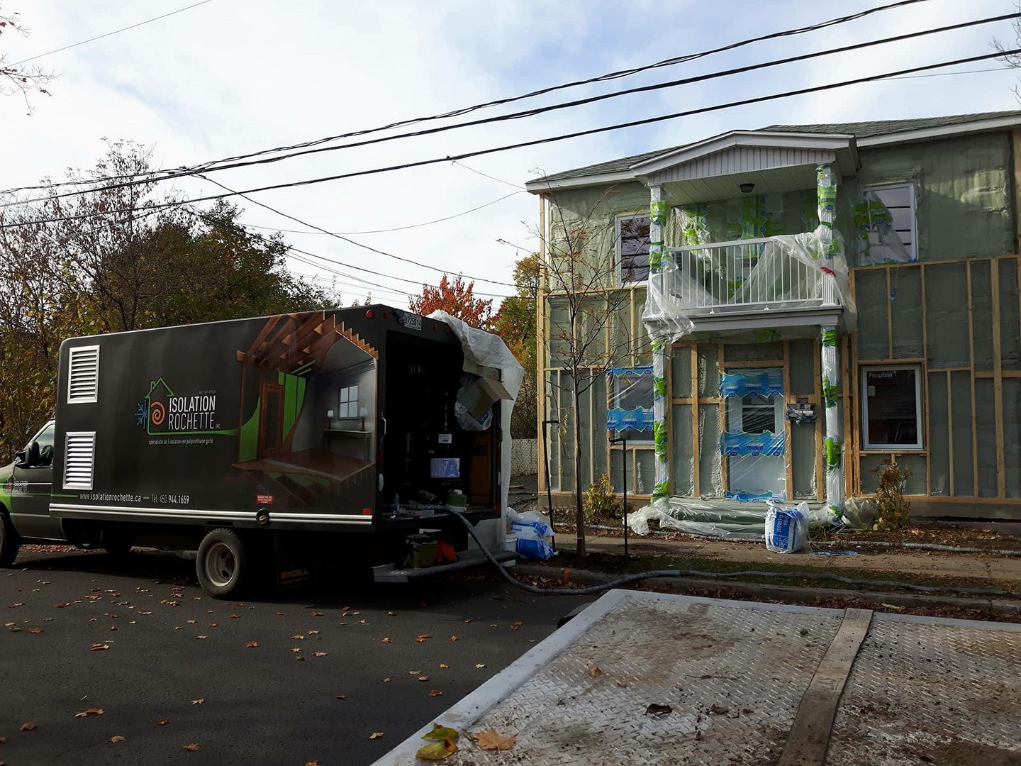 Camion garé à côté d'une maison en construction, pulvérisant de l'isolant.