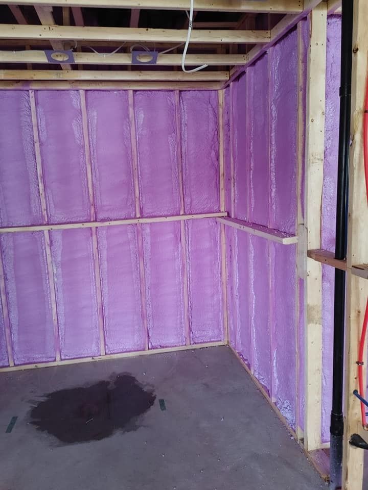 Murs de sous-sol à ossature bois avec isolation violette. Flaque d'eau sur le sol en béton.