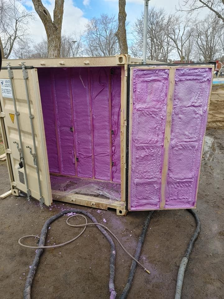 Conteneur maritime aux portes ouvertes, isolé avec de la mousse pulvérisée rose. Câbles posés au sol.