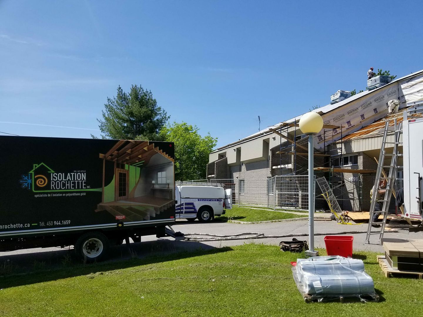 Un camion avec un logo d'isolation de bâtiment à côté d'un bâtiment en cours de construction.