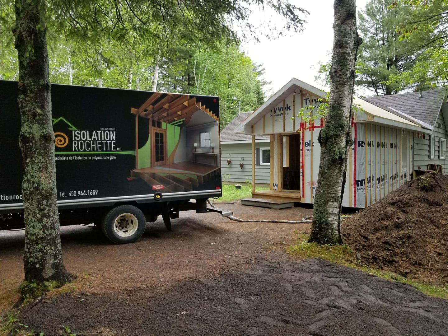 Camion stationné près d'une maison en construction; le logo indique des services d'isolation.