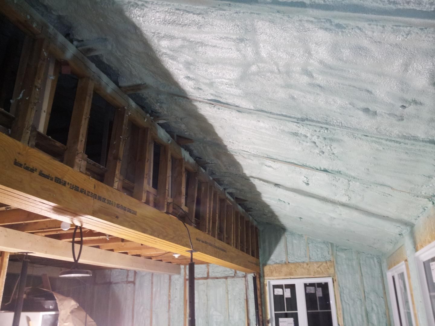 Vue intérieure d'un projet de construction avec isolation en mousse pulvérisée au plafond et aux murs.