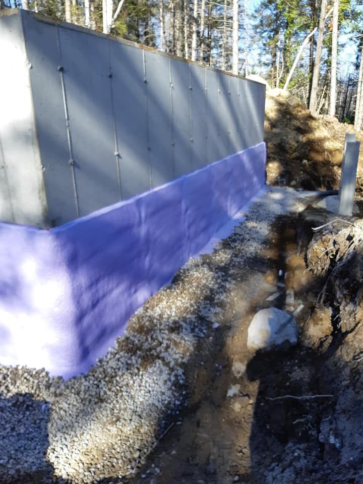 Un mur en béton avec une membrane imperméable bleue en cours d'installation à l'extérieur.