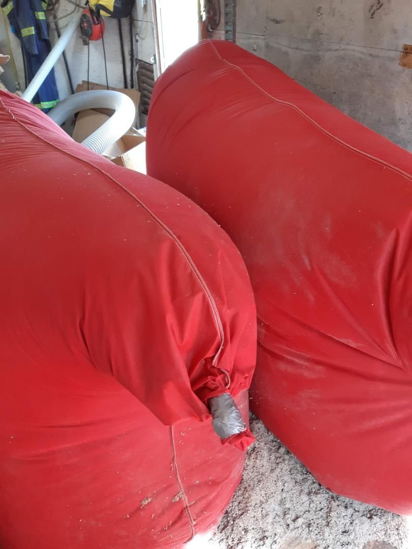 Deux grands sacs rouges gonflés, probablement destinés à la construction ou au sauvetage, reposent sur une surface poussiéreuse.