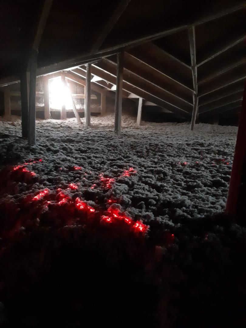 Grenier avec isolation éclairé par la lumière du soleil; lumières rouges brillantes au premier plan.