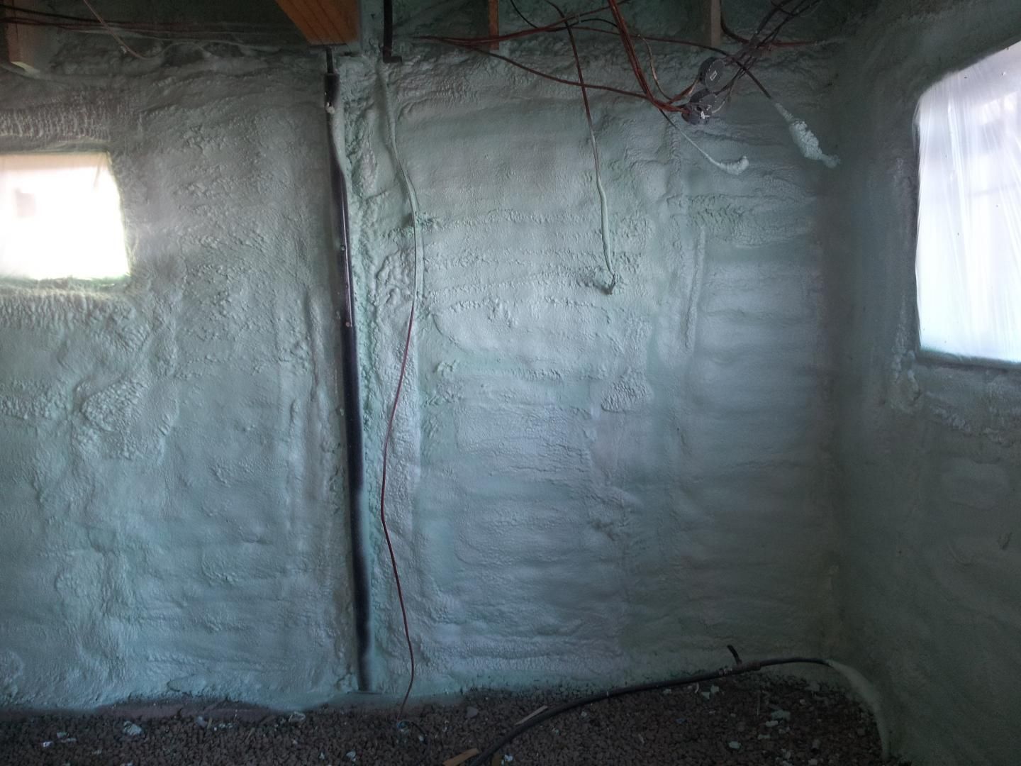 Isolation en mousse recouvrant les murs intérieurs du sous-sol, avec fenêtres de chaque côté.