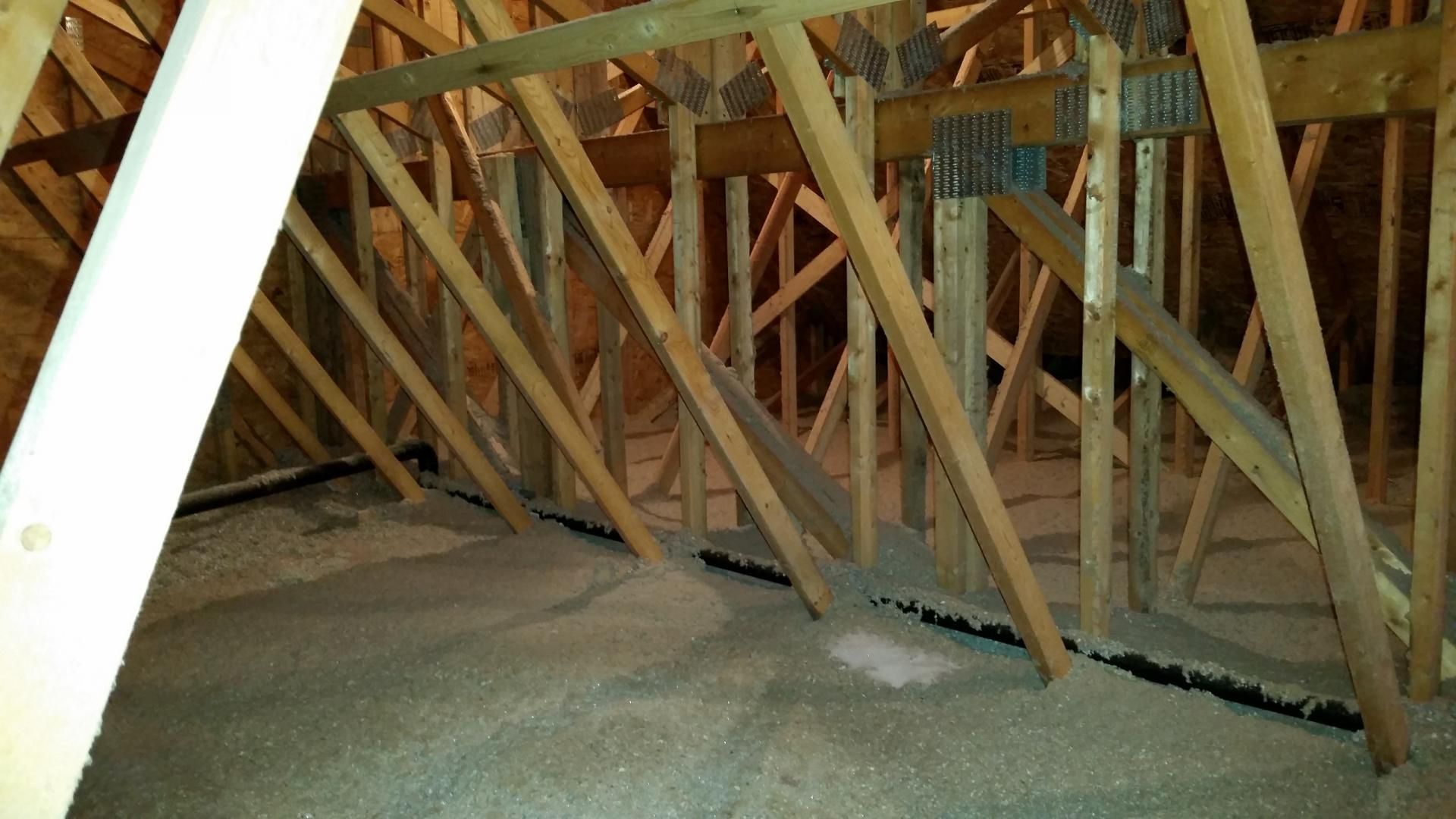 Intérieur d'un grenier avec chevrons en bois et isolation.