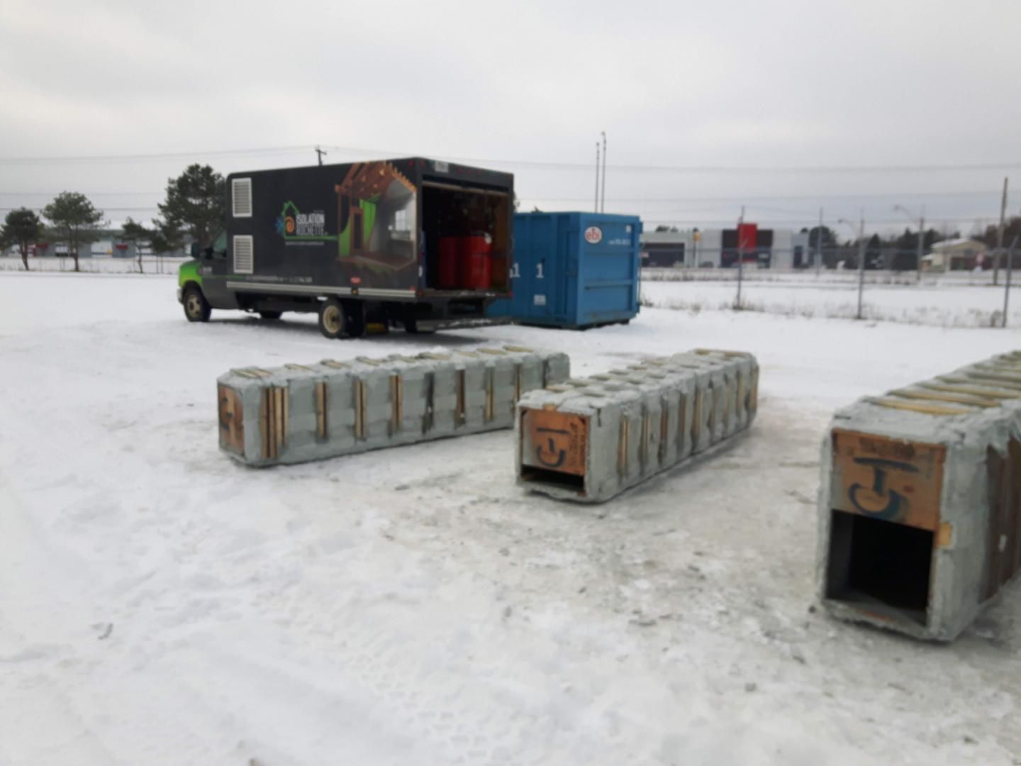 Un camion avec porte ouverte, blocs de béton et sol enneigé.