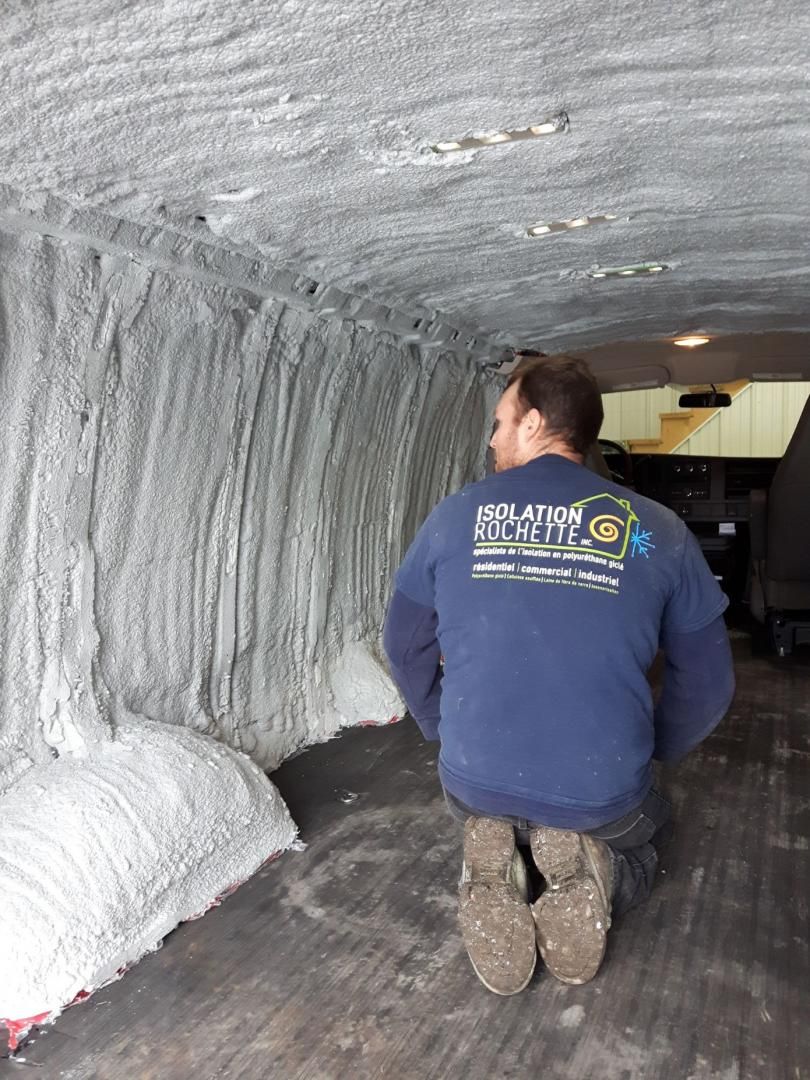 Un homme est agenouillé dans l'intérieur d'un camion recouvert d'une isolation blanche.