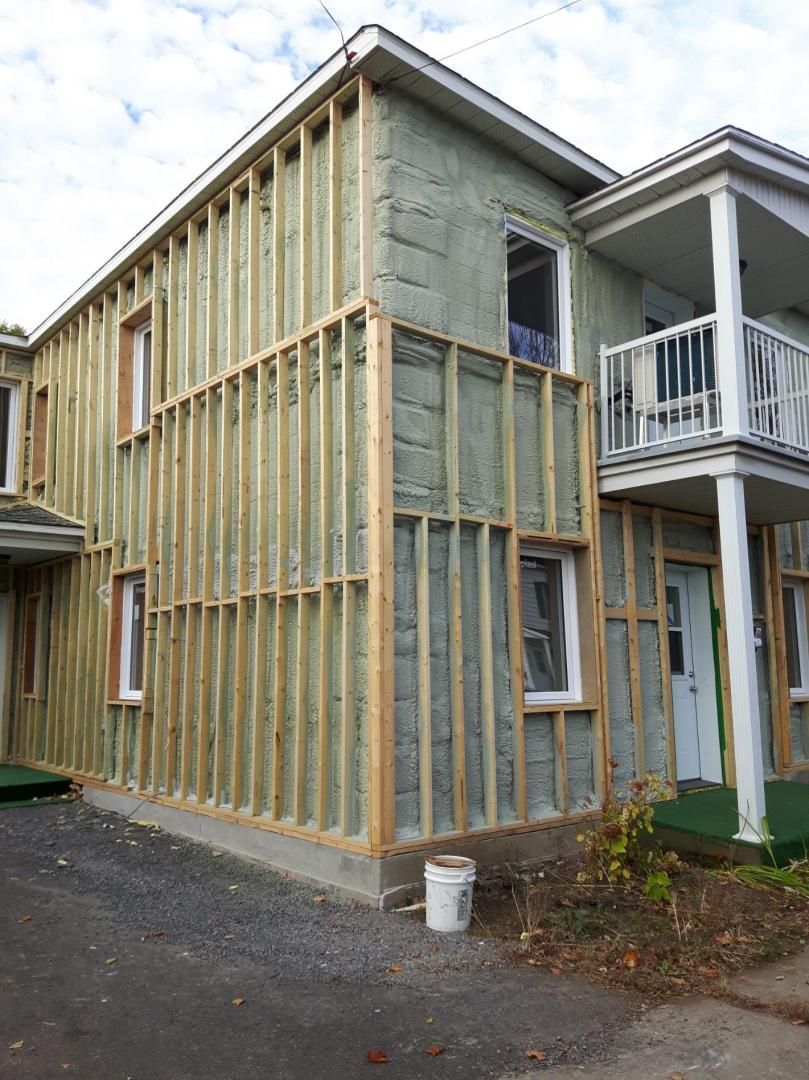 Bâtiment extérieur en cours de rénovation ; ossature bois recouvrant la façade, isolation apparente.