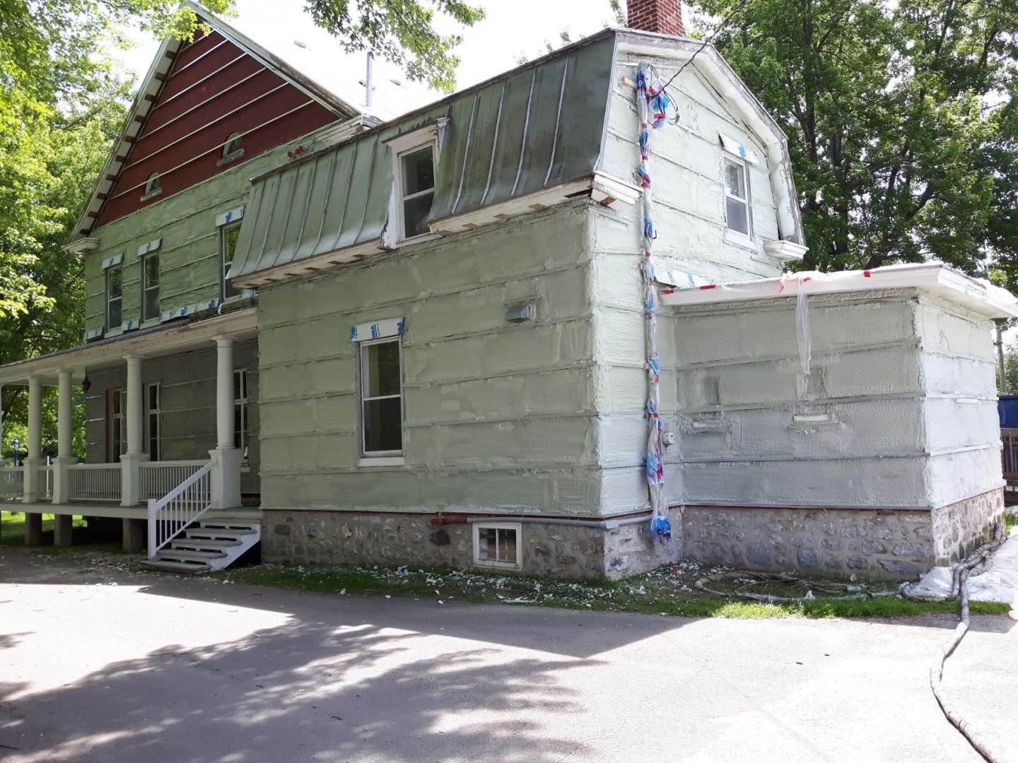 Serre avec porche, façade patinée et toit rouge rouillé.
