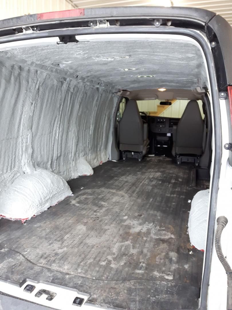 Intérieur de fourgonnette vide avec plancher sombre et parois claires et isolées.