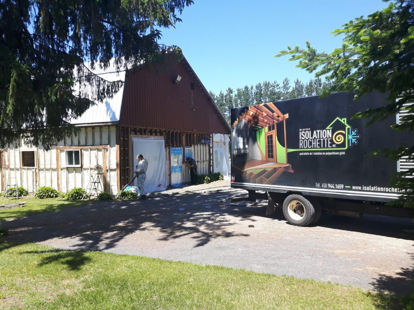 Camion stationné près d'une grange en cours de rénovation, ouvrier à l'extérieur.