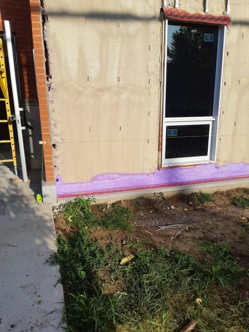 Mur extérieur avec fenêtre, briques apparentes et isolation. Isolation en mousse violette visible.