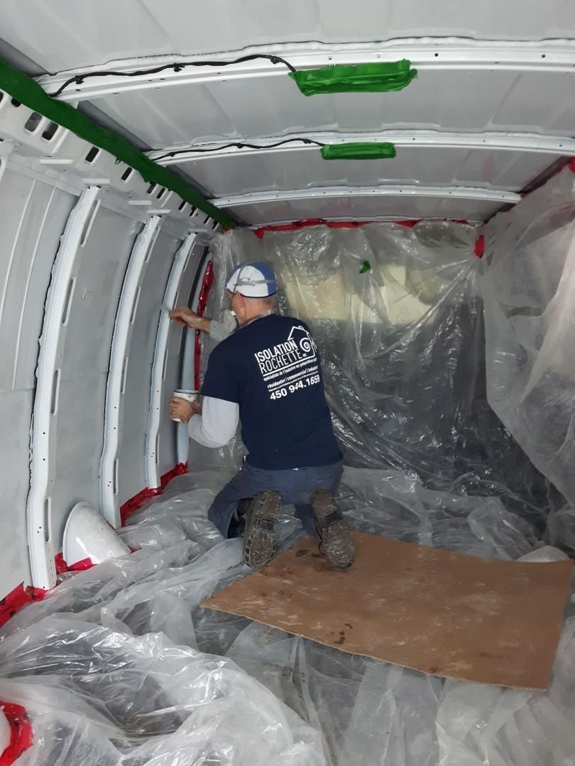 Un homme peint à l'intérieur d'une camionnette blanche, masqué pour peindre.