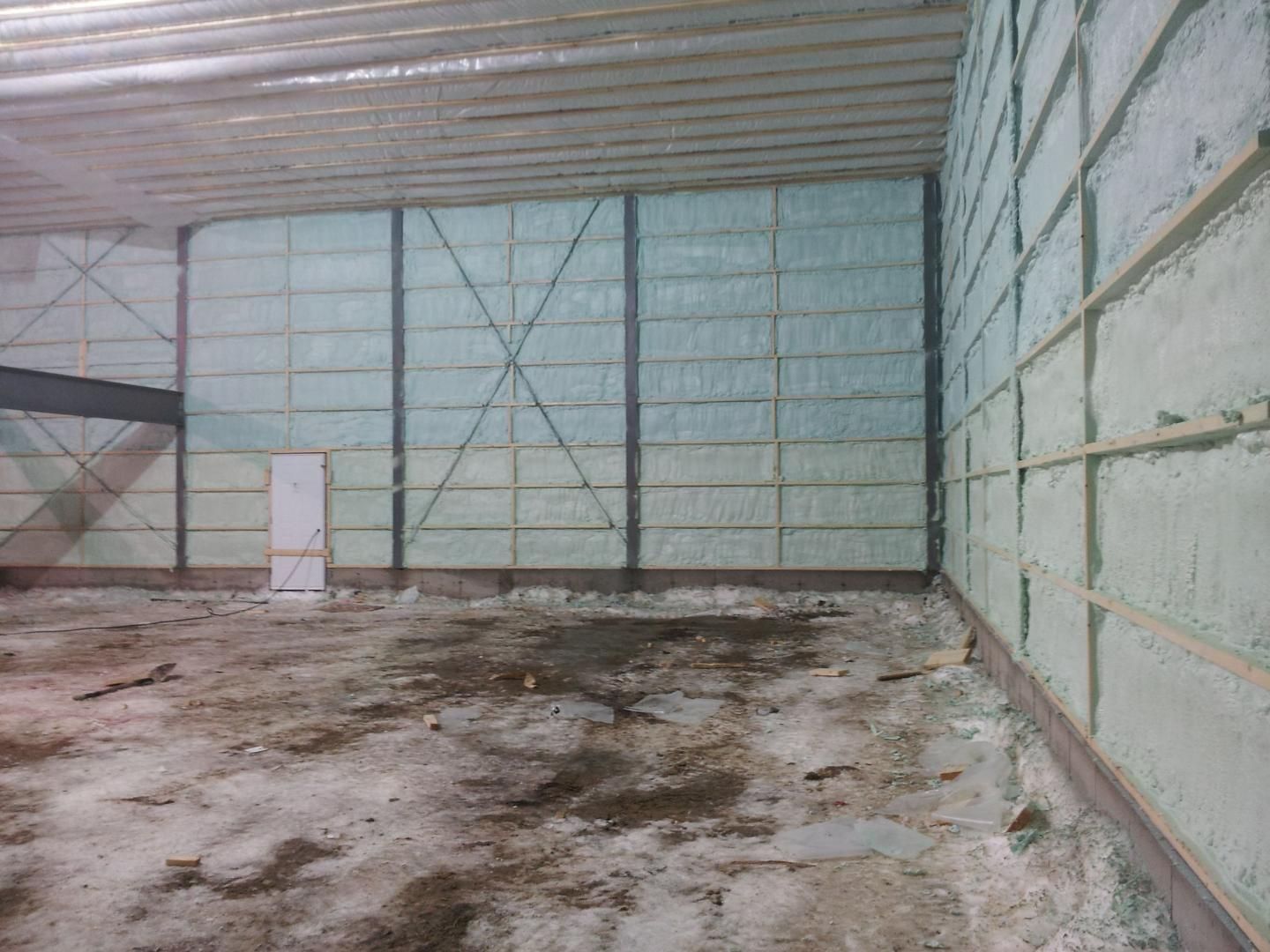 Vue intérieure d'un bâtiment en construction, avec isolation en mousse projetée sur les murs.