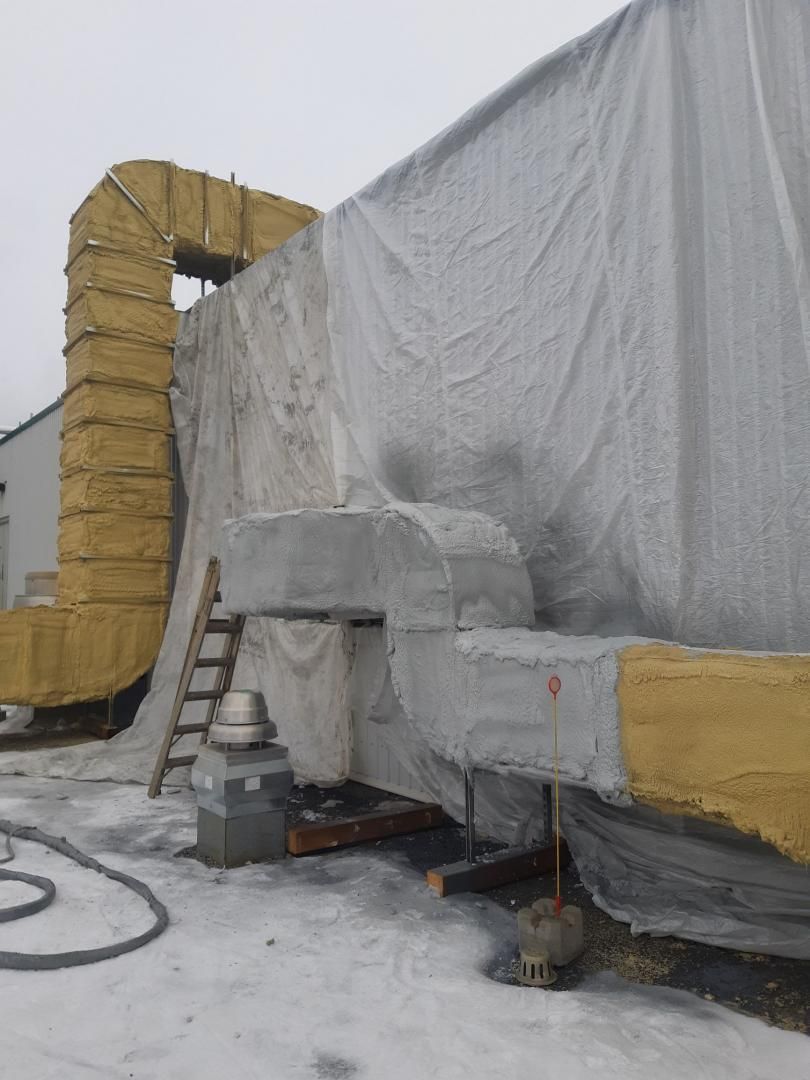 Unité de CVC sur le toit recouverte d'une bâche, avec conduits isolés, échelle et neige.